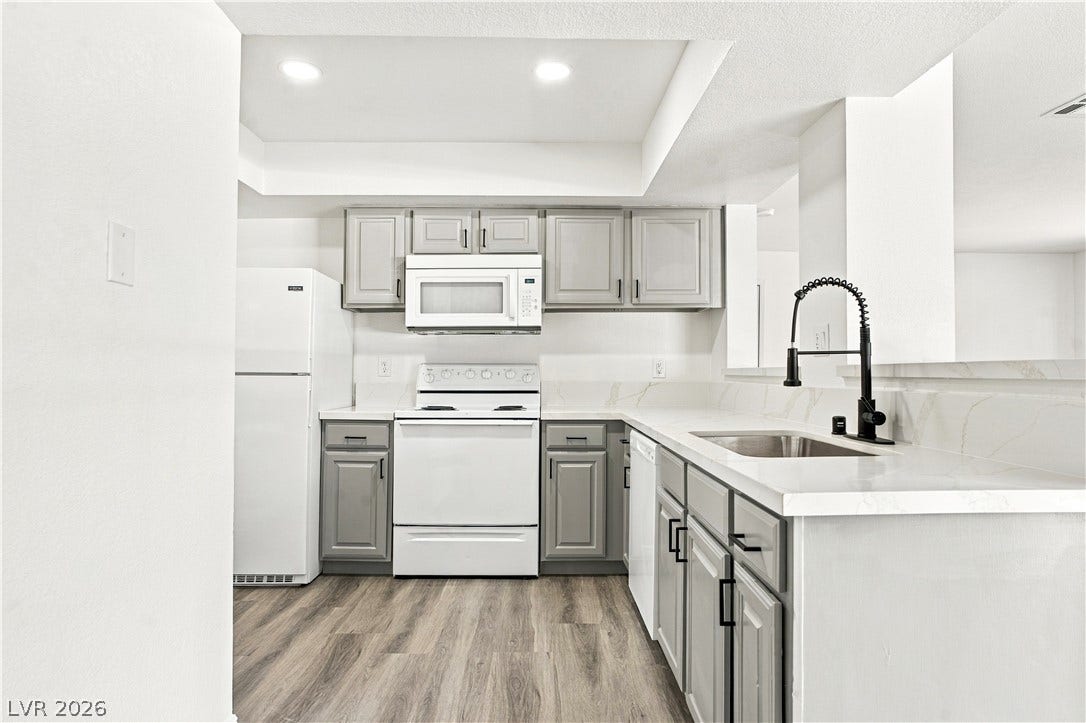6800 Lake Mead, #2117, Las Vegas, NV 89156 Recessed lighting and stone counters elevate this modern kitchen featuring vinyl plank flooring.