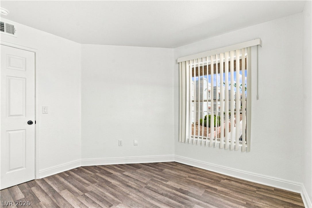 6800 Lake Mead, #2117, Las Vegas, NV 89156 Smooth wood-style flooring and a wide window with integrated vertical blinds define this versatile room.