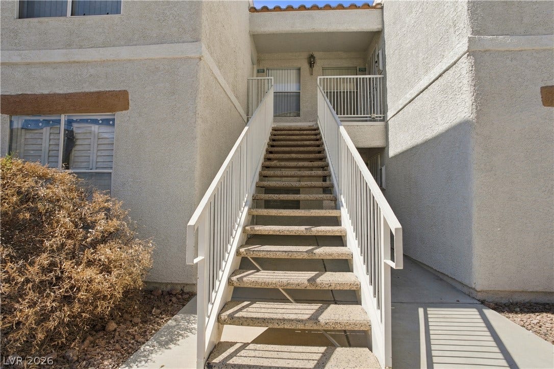 6800 Lake Mead, #2117, Las Vegas, NV 89156 Concrete stairs with metal railings ascend to a covered entryway under a tiled roofline.