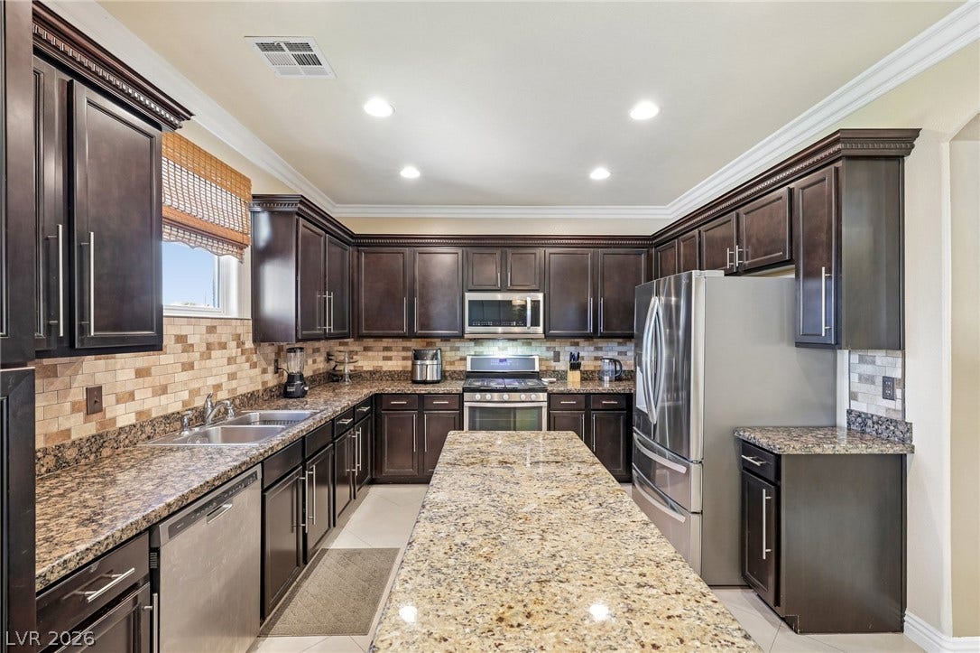 4024 Solar System Street, North Las Vegas, NV 89032 Rich dark cabinetry and speckled granite countertops define this classic kitchen layout.