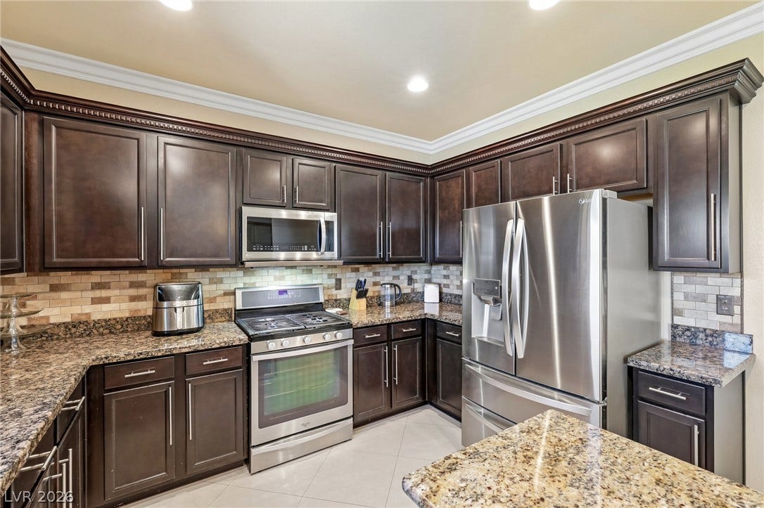 4024 Solar System Street, North Las Vegas, NV 89032 Gleaming granite countertops complement dark wood cabinetry and polished tile flooring in this kitchen.