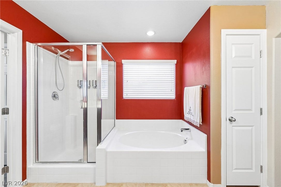 4024 Solar System Street, North Las Vegas, NV 89032 A glass-enclosed shower stands adjacent to a built-in soaking tub beneath a large window.