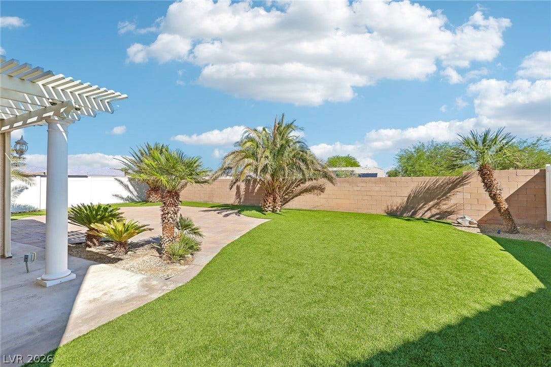 4024 Solar System Street, North Las Vegas, NV 89032 Lush green turf and tropical palms create an inviting backyard oasis framed by a block wall.