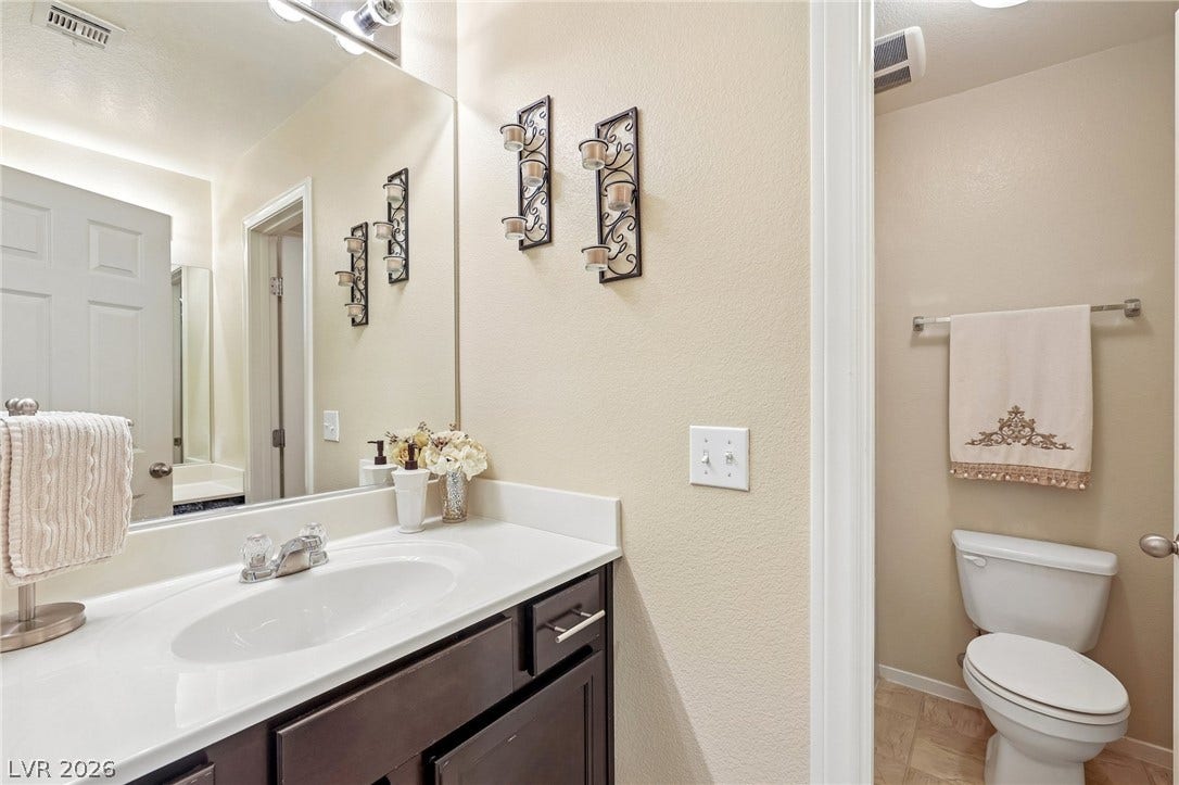4024 Solar System Street, North Las Vegas, NV 89032 An inviting powder room features a classic dark wood vanity and clean solid surface countertops.