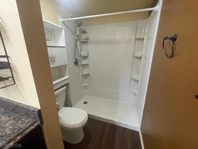 3550 Bay Sands Drive, #1017, Laughlin, NV 89029 A compact bathroom features a walk-in shower insert, dark laminate flooring, and built-in shelving.