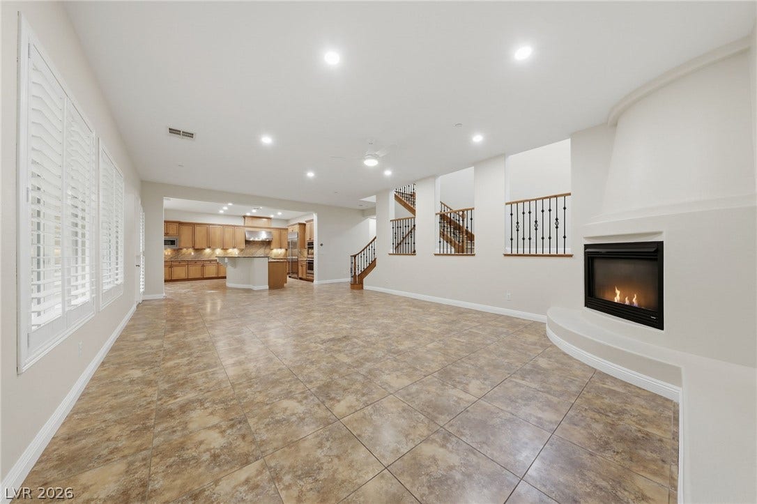1357 Enchanted River Drive, Henderson, NV 89012 Tiled flooring and a modern fireplace define this expansive main-level living space.