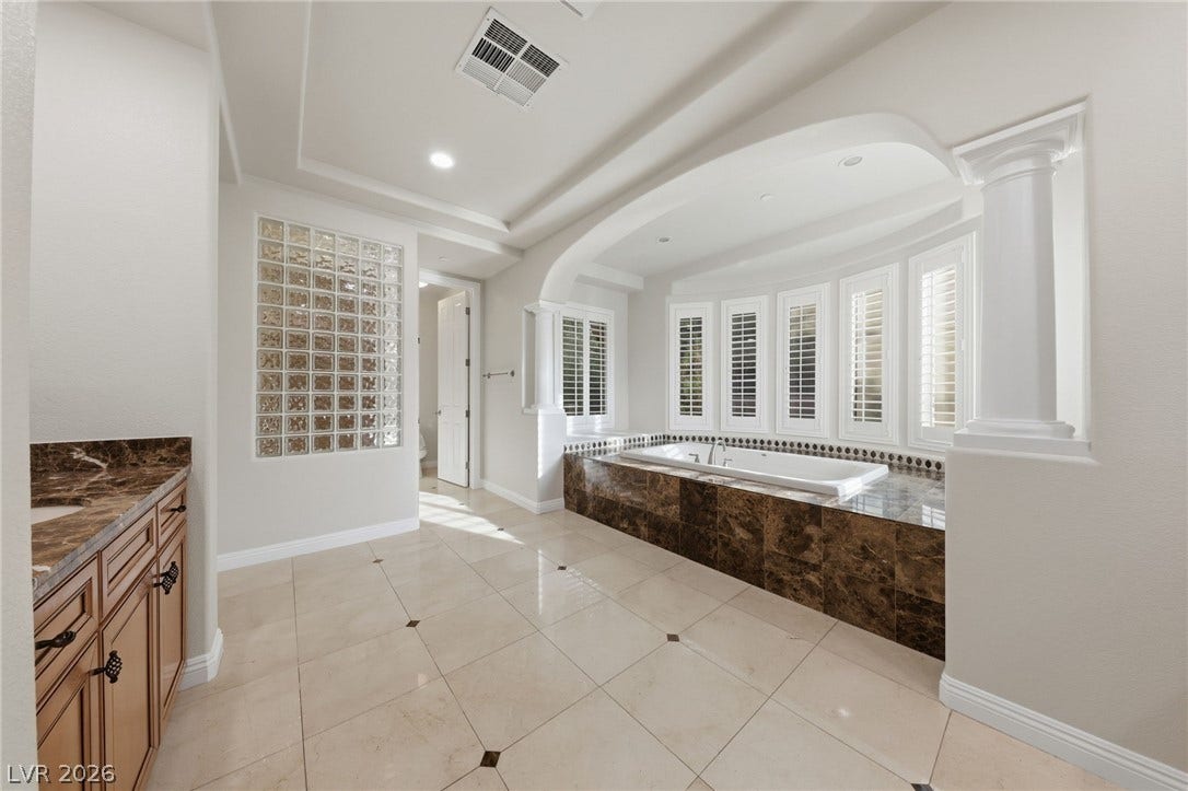 1357 Enchanted River Drive, Henderson, NV 89012 Polished tile flooring and an elegant arched alcove elevate this primary bath space.