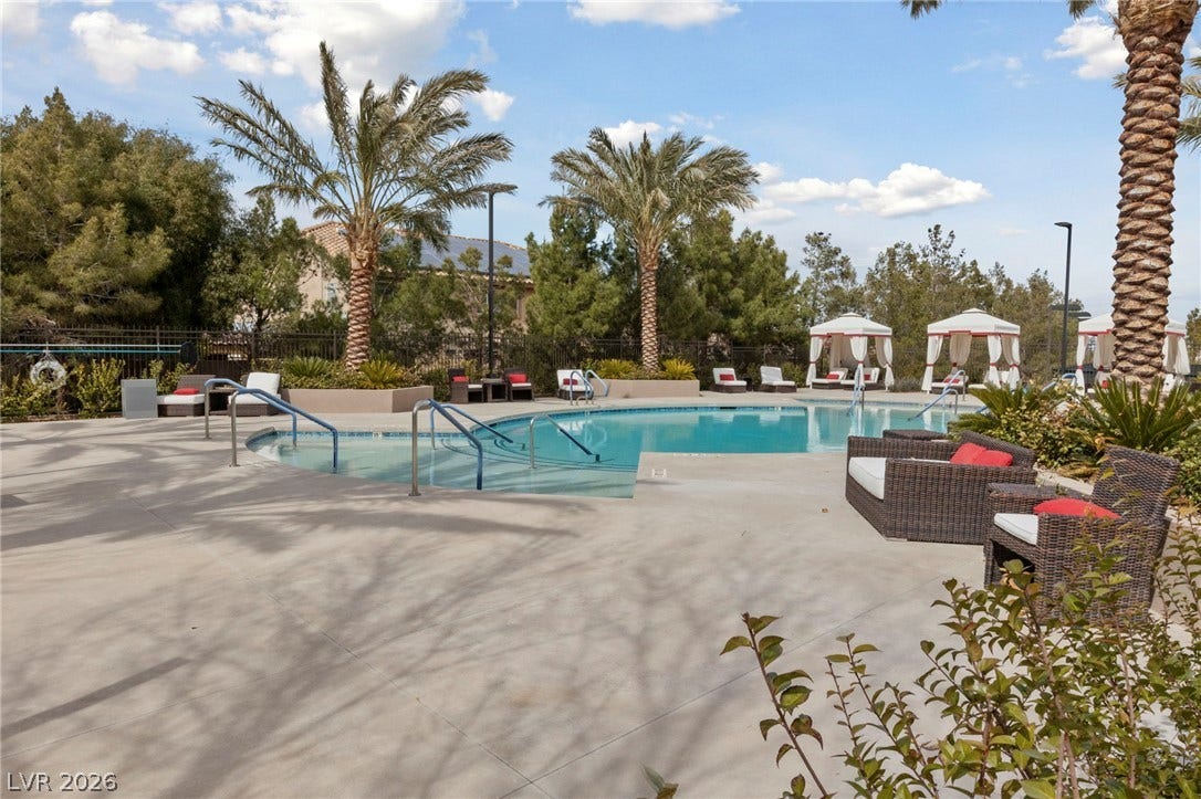 1357 Enchanted River Drive, Henderson, NV 89012 Lush palm trees and ample concrete decking frame a sparkling community swimming pool.