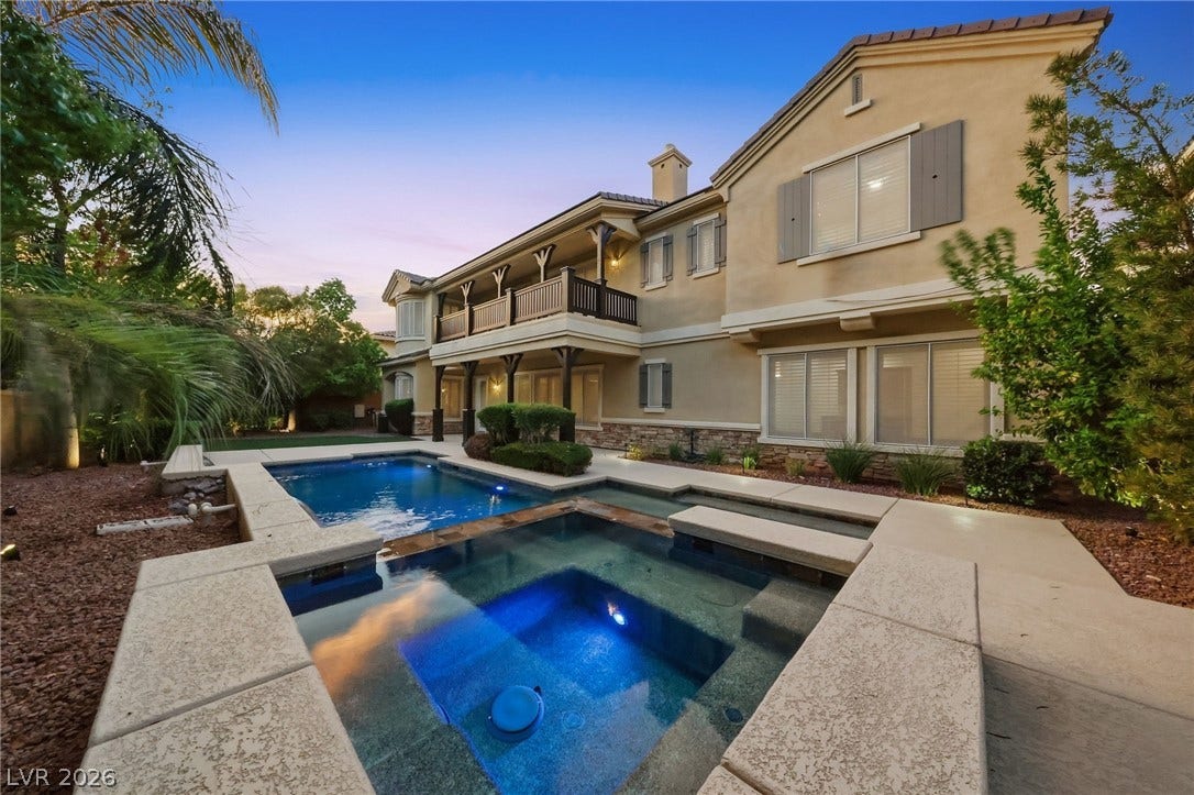 1357 Enchanted River Drive, Henderson, NV 89012 An inviting backyard oasis features a multi-tiered pool and spa alongside a classic stucco exterior.