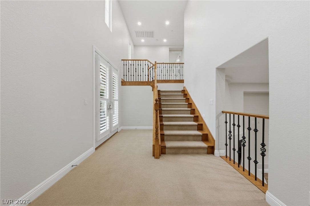 1357 Enchanted River Drive, Henderson, NV 89012 An open second-floor landing showcases carpeted stairs, wrought-iron railings, and high ceilings.