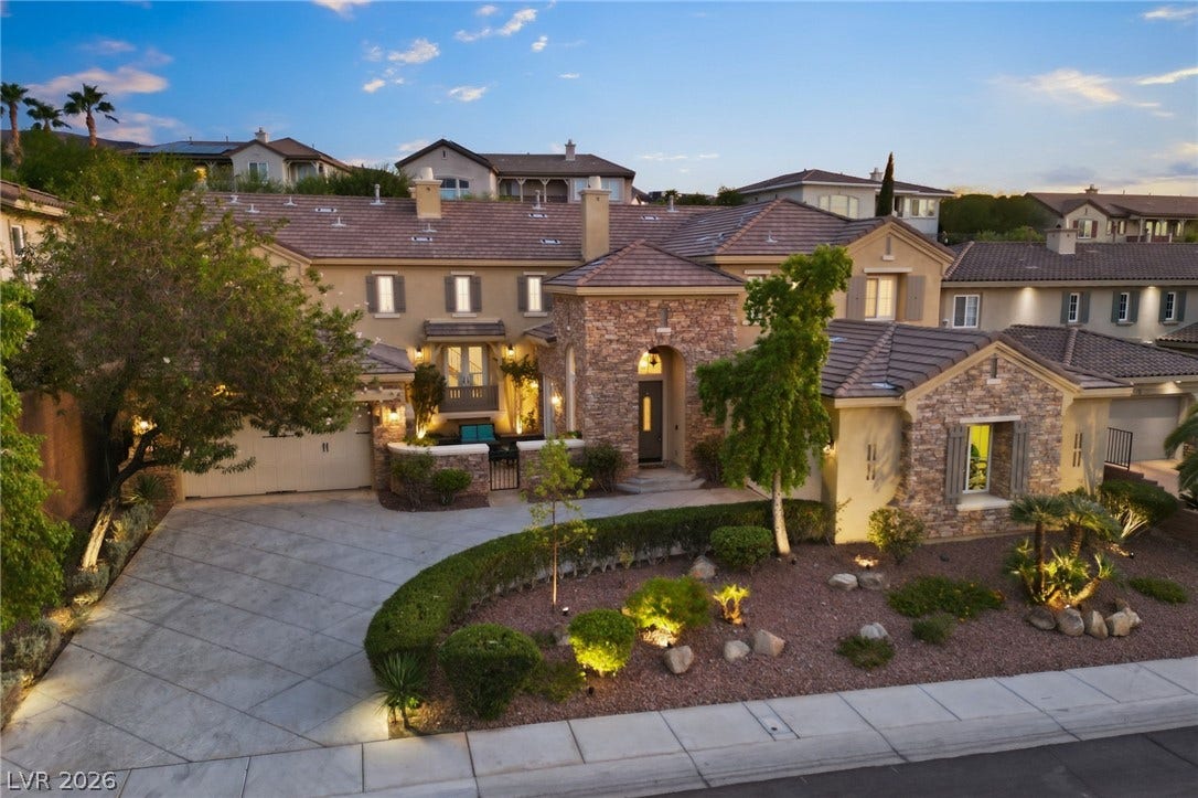 1357 Enchanted River Drive, Henderson, NV 89012 Stately stone accents and a manicured driveway create an inviting entrance under the twilight sky.