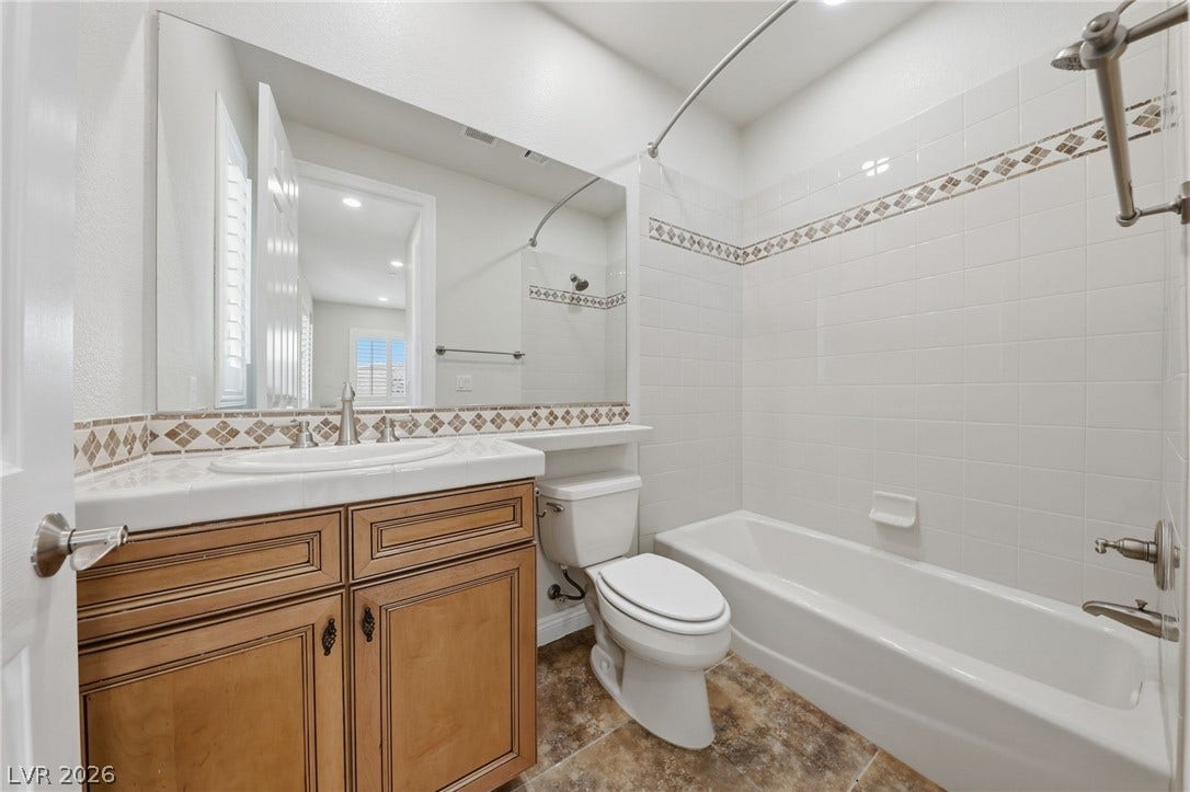 1357 Enchanted River Drive, Henderson, NV 89012 Tiled walls and a classic wood vanity define this clean, practical bathroom layout.