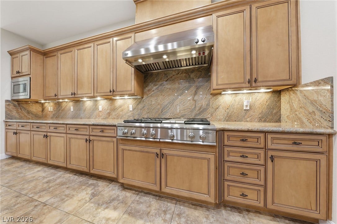 1357 Enchanted River Drive, Henderson, NV 89012 Richly toned wood cabinetry, matching granite countertops, and polished tile floors define this culinary space.