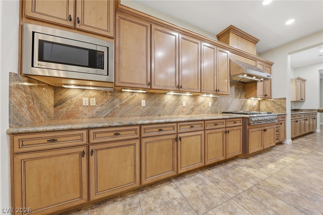 1357 Enchanted River Drive, Henderson, NV 89012 Rich wood cabinetry paired with elegant stone countertops creates a timeless kitchen design.