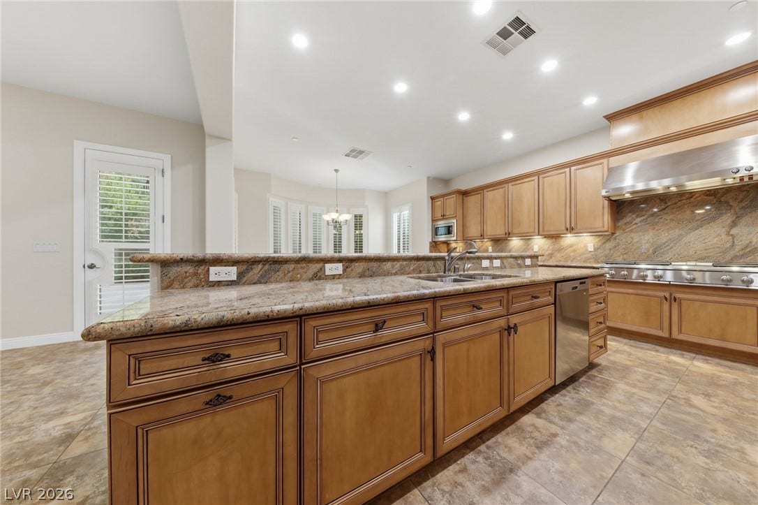 1357 Enchanted River Drive, Henderson, NV 89012 Rich wood cabinetry and expansive granite countertops define this well-appointed gourmet kitchen space.
