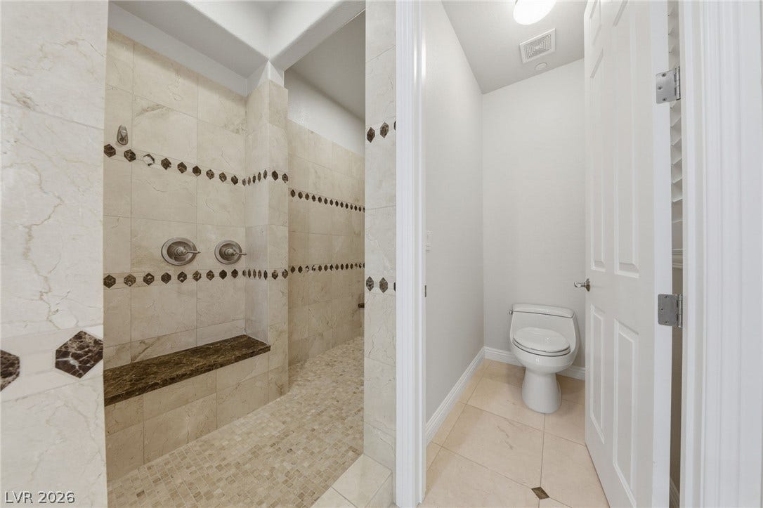 1357 Enchanted River Drive, Henderson, NV 89012 Fine tilework and a built-in stone bench highlight this spacious walk-in shower design.