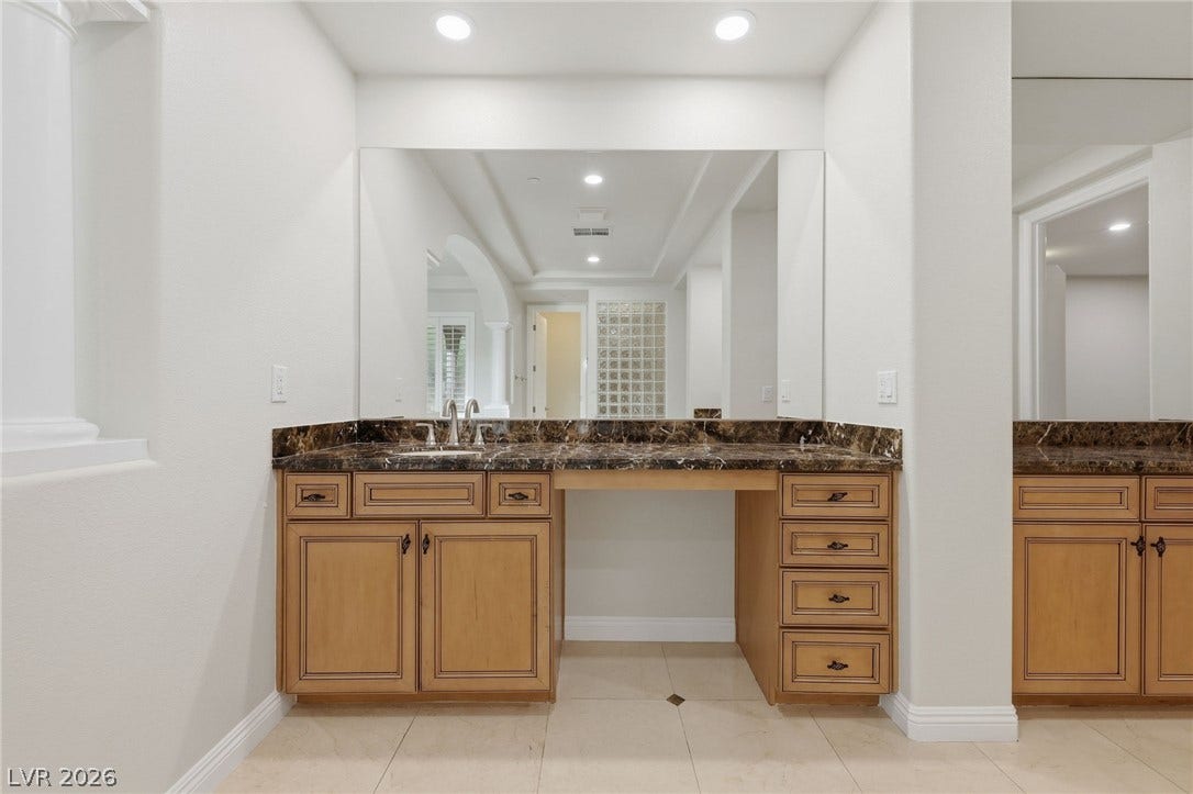 1357 Enchanted River Drive, Henderson, NV 89012 Gleaming stone countertops and classic wood cabinetry anchor this spacious master bath vanity station.