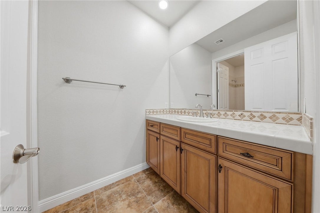 1357 Enchanted River Drive, Henderson, NV 89012 Tiled countertops and warm wood cabinetry define this functional vanity space.
