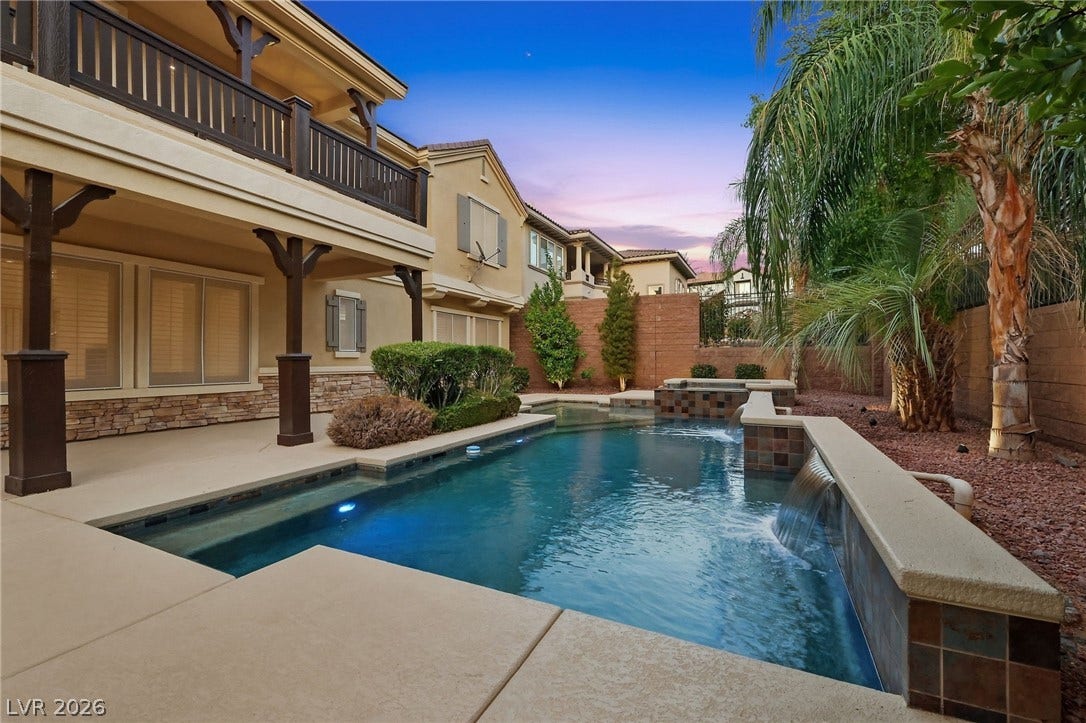 1357 Enchanted River Drive, Henderson, NV 89012 An inviting backyard oasis features a swimming pool with integrated waterfalls and a covered patio.
