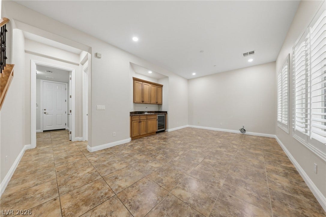 1357 Enchanted River Drive, Henderson, NV 89012 Tile flooring and plantation shutters accent this versatile living area featuring a built-in wet bar.