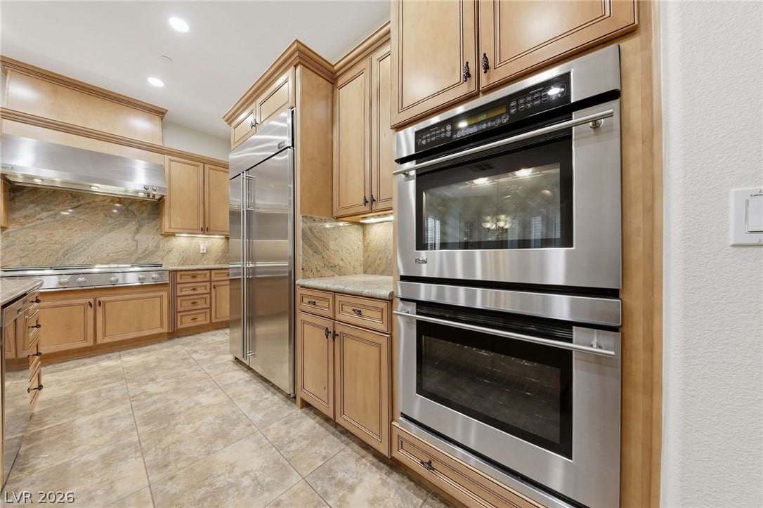 1357 Enchanted River Drive, Henderson, NV 89012 Gleaming stone tile flooring and traditional wood cabinetry define this gourmet kitchen space.