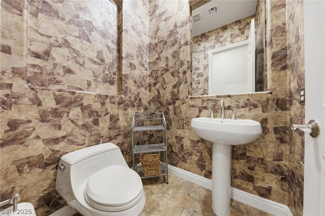 1357 Enchanted River Drive, Henderson, NV 89012 Unique stone-patterned walls pair with a classic pedestal sink in this compact powder room.