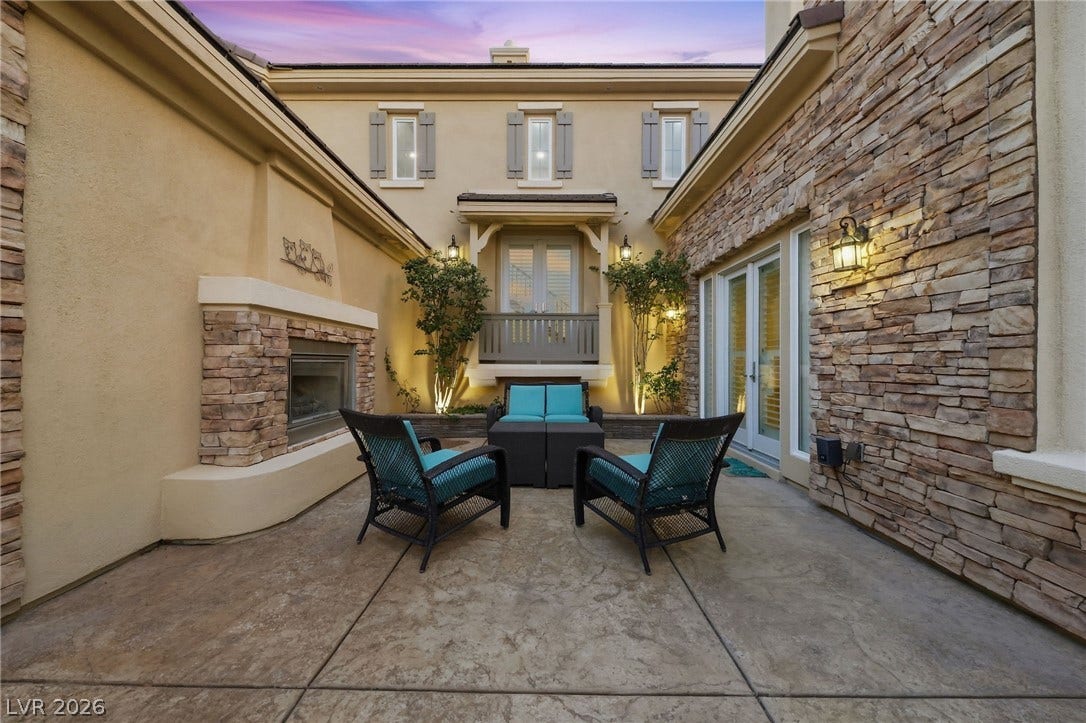 1357 Enchanted River Drive, Henderson, NV 89012 An inviting stone-accented courtyard features an outdoor fireplace and textured concrete flooring.