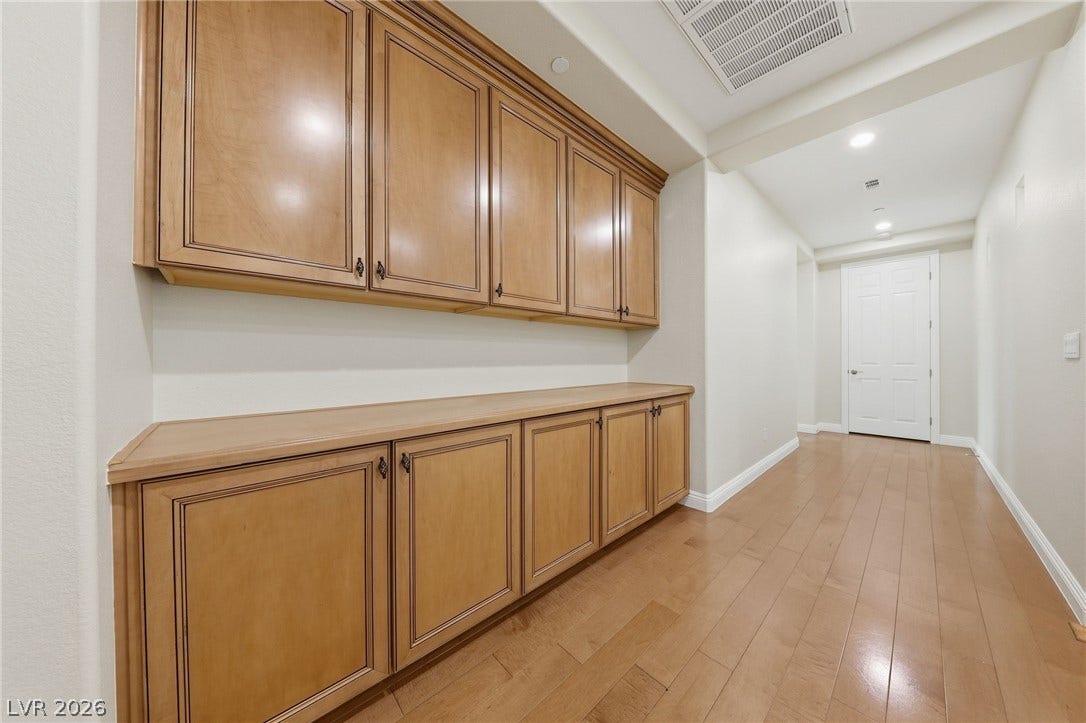 1357 Enchanted River Drive, Henderson, NV 89012 Ample built-in storage cabinets line this wide hallway featuring polished wood flooring.