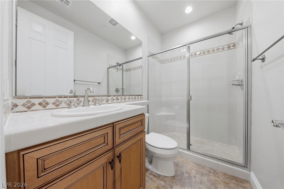 1357 Enchanted River Drive, Henderson, NV 89012 Tiled vanity countertops and a spacious glass-enclosed shower highlight this functional bathroom.