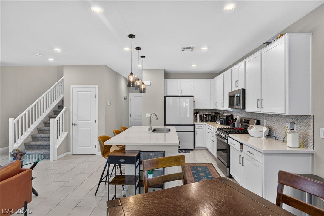 2719 High Echelon Road, North Las Vegas, NV 89086 Gleaming stone countertops and white cabinetry define this open kitchen adjoining the staircase.