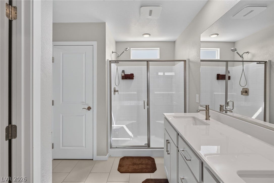 2719 High Echelon Road, North Las Vegas, NV 89086 A contemporary bathroom features a glass-enclosed walk-in shower and a dual-sink vanity.