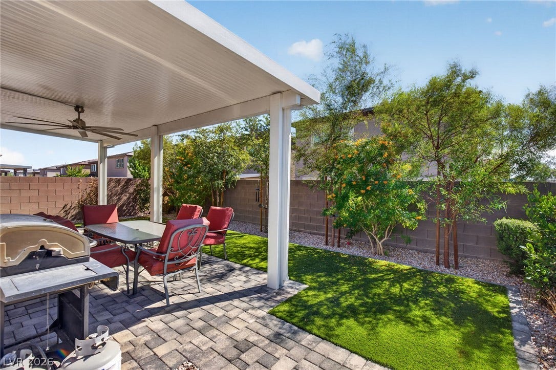 2719 High Echelon Road, North Las Vegas, NV 89086 An inviting covered patio features neat paver flooring alongside a manicured green lawn.
