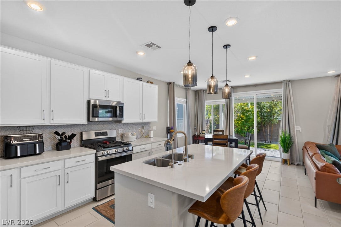 2719 High Echelon Road, North Las Vegas, NV 89086 Gleaming stone countertops and a spacious central island anchor this open-concept kitchen.
