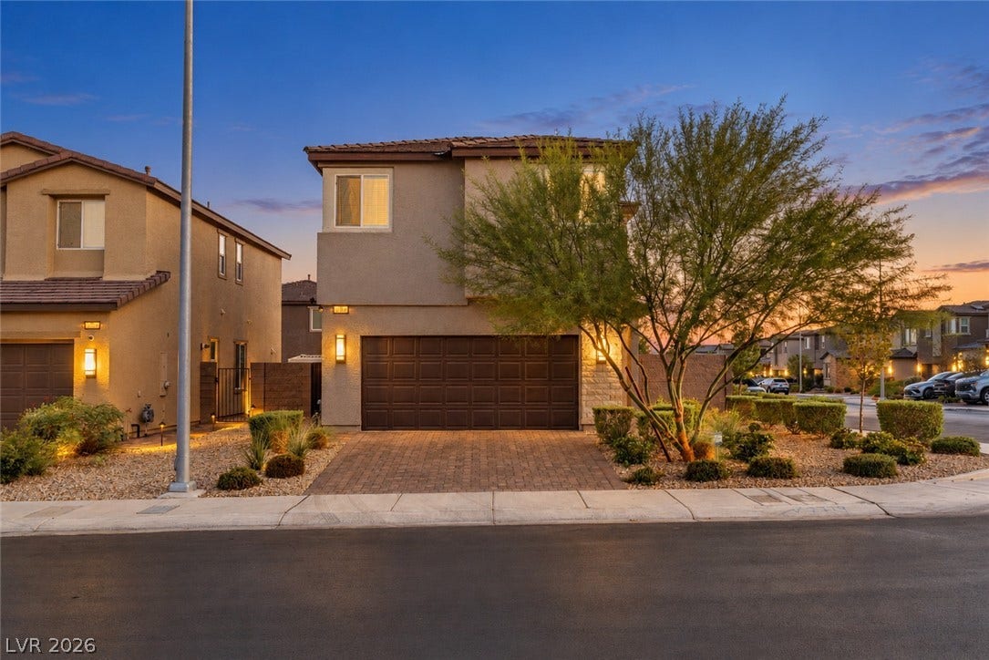 2719 High Echelon Road, North Las Vegas, NV 89086 Warm exterior lighting accents this modern stucco home featuring a paved driveway and desert landscaping.