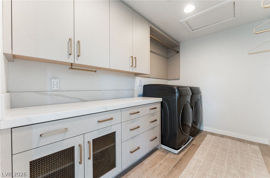 12424 Point Sierra Street, Las Vegas, NV 89138 An organized laundry room offers ample custom cabinetry, stone countertops, and modern appliances on wood floors.