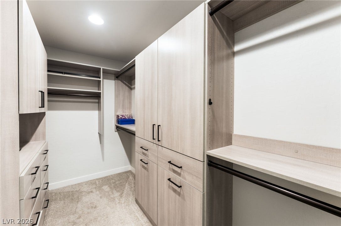 12424 Point Sierra Street, Las Vegas, NV 89138 Custom built-in cabinetry and hanging rods maximize storage within this carpeted walk-in closet.