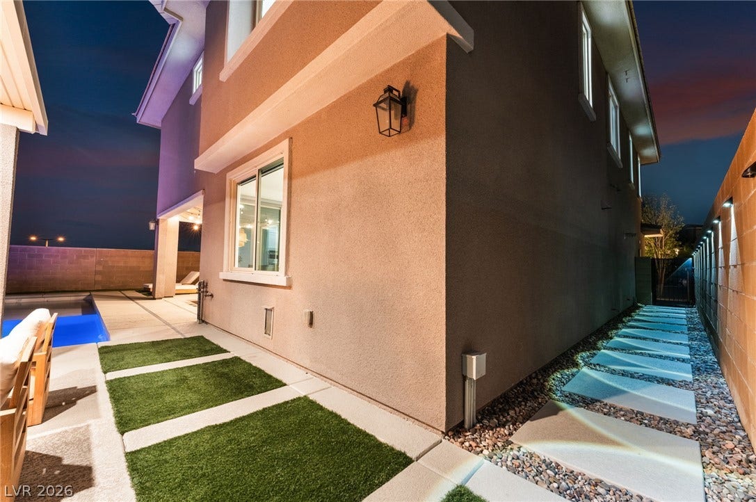 12424 Point Sierra Street, Las Vegas, NV 89138 A structured stone pathway runs alongside the stucco exterior under illuminated night skies.