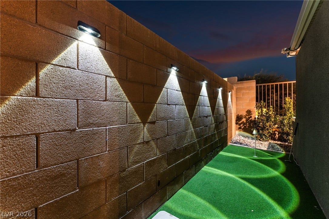 12424 Point Sierra Street, Las Vegas, NV 89138 Integrated wall lighting illuminates the private backyard putting green at dusk.
