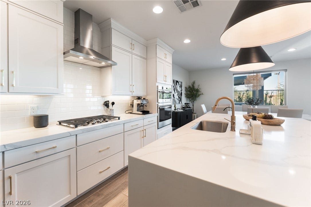 12424 Point Sierra Street, Las Vegas, NV 89138 Gleaming stone countertops and a spacious waterfall island anchor this open-concept modern kitchen space.
