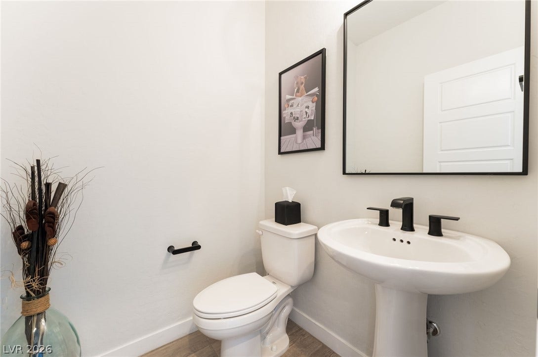 12424 Point Sierra Street, Las Vegas, NV 89138 A clean powder room featuring a classic pedestal sink and modern black fixtures.