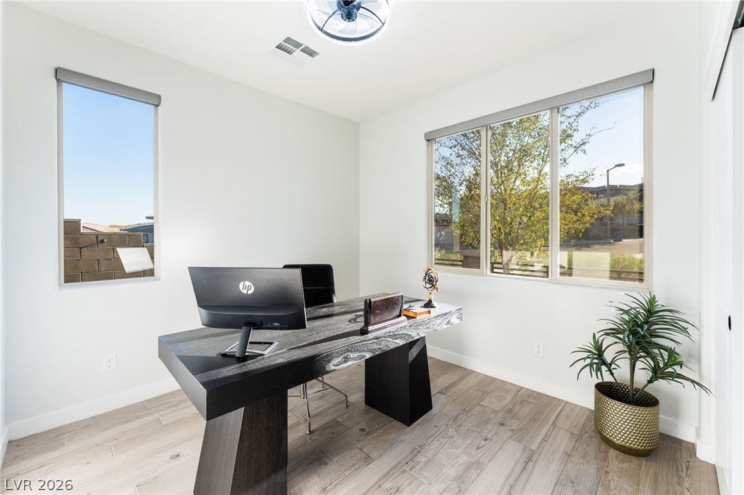 12424 Point Sierra Street, Las Vegas, NV 89138 A quiet home office features light wood-look flooring and multiple windows overlooking the yard.
