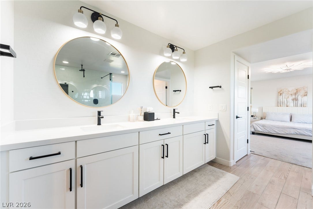 12424 Point Sierra Street, Las Vegas, NV 89138 A sleek double vanity with modern round mirrors highlights this bright bathroom space.