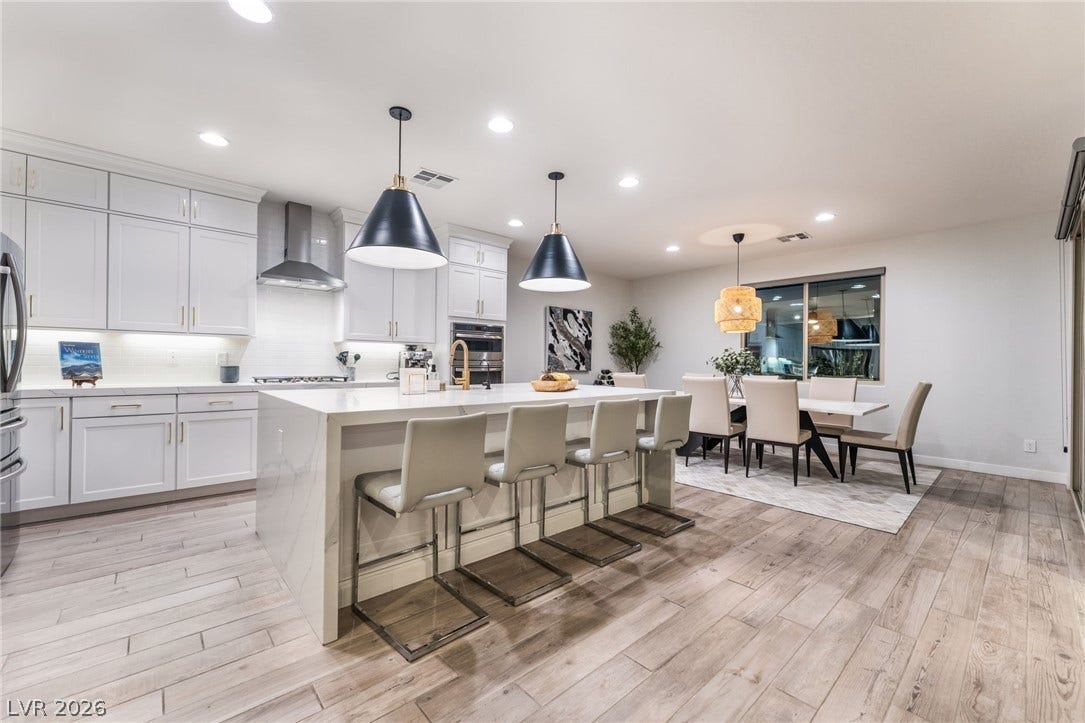12424 Point Sierra Street, Las Vegas, NV 89138 An open kitchen with white cabinetry and wood floors transitions smoothly into the dining area.