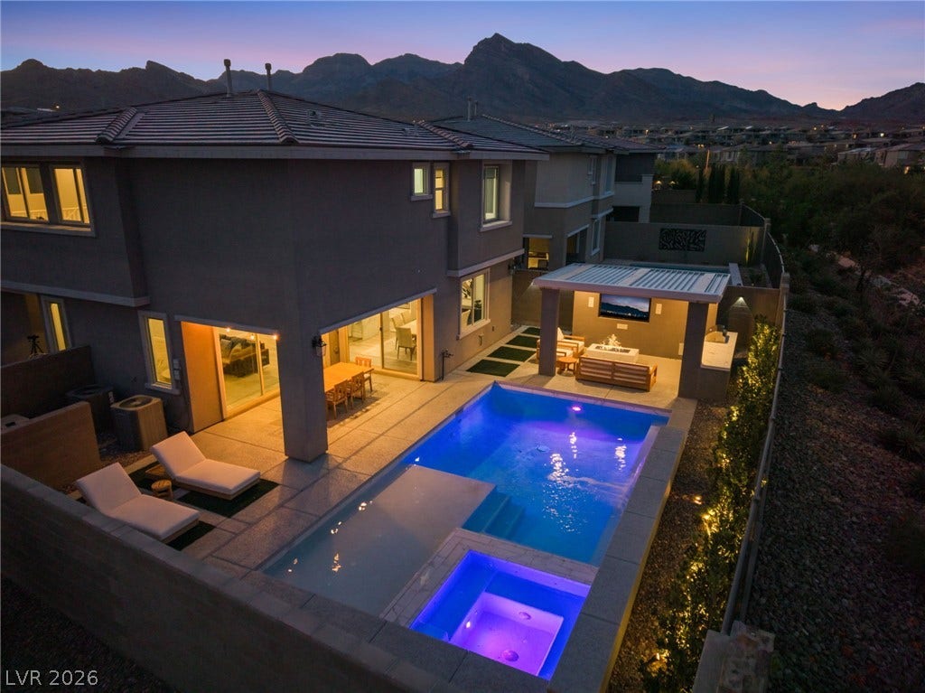 12424 Point Sierra Street, Las Vegas, NV 89138 An illuminated pool and spa sit below majestic mountain silhouettes under a twilight sky.