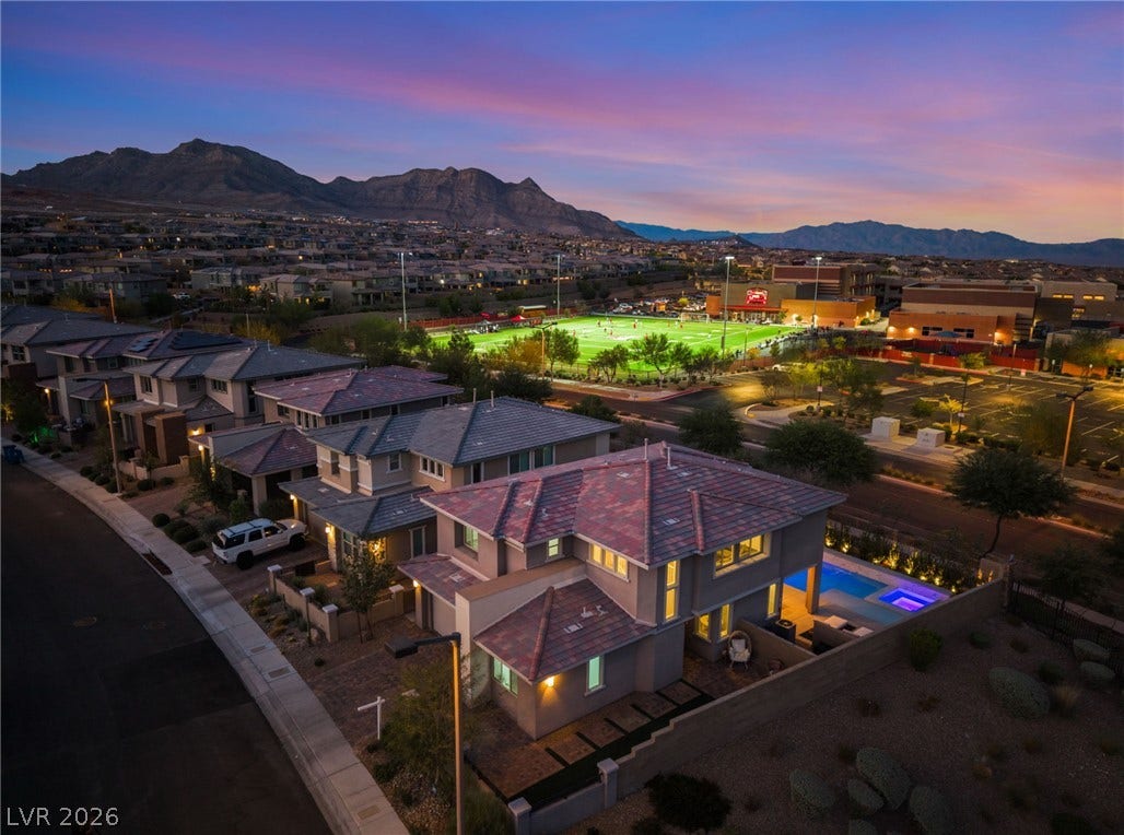 12424 Point Sierra Street, Las Vegas, NV 89138 Dramatic mountain peaks frame this modern neighborhood captured under a vivid twilight sky.