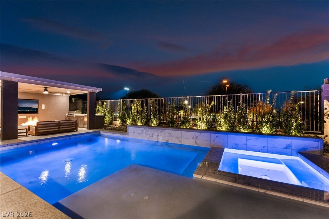12424 Point Sierra Street, Las Vegas, NV 89138 An inviting backyard oasis features a gleaming swimming pool and spa beneath dramatic twilight skies.
