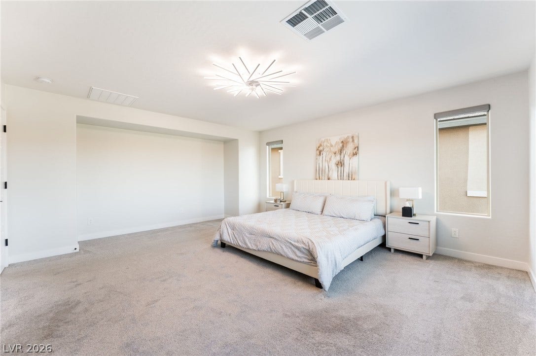 12424 Point Sierra Street, Las Vegas, NV 89138 A spacious bedroom features plush carpeting, a large wall alcove, and a modern light fixture.