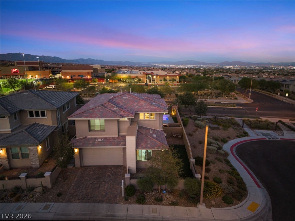12424 Point Sierra Street, Las Vegas, NV 89138 An elevated perspective showcases the modern multi-level exterior nestled against a vibrant twilight horizon.