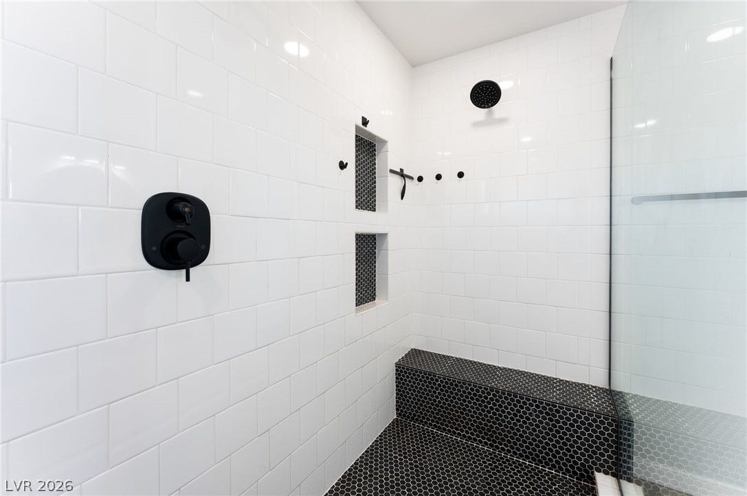 12424 Point Sierra Street, Las Vegas, NV 89138 White subway tiling contrasts with dark penny round tiles in this modern walk-in shower.