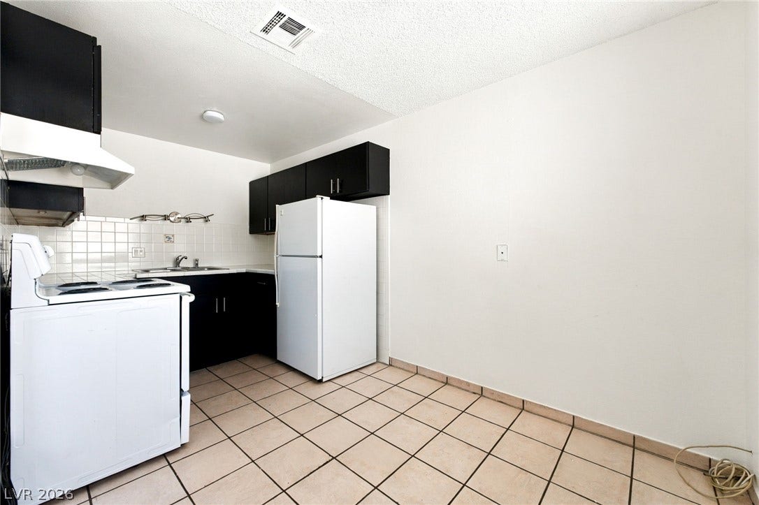 2553 Ellis Street, North Las Vegas, NV 89030 Tiled flooring and dark cabinetry define this functional kitchen layout.